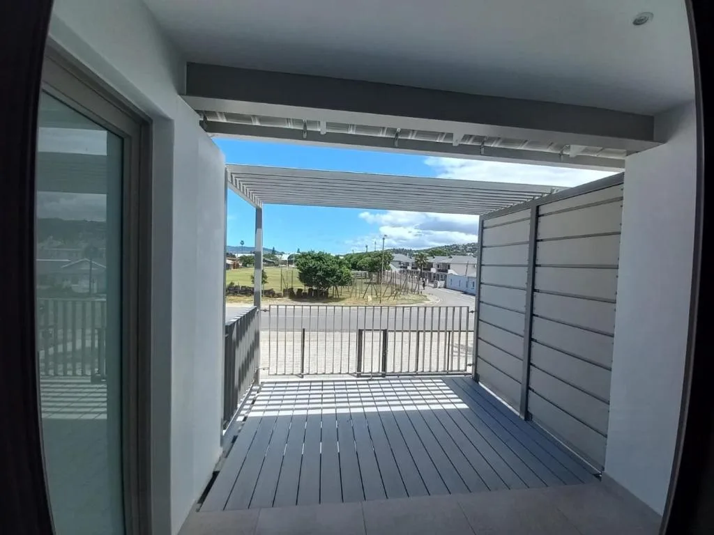 Modern covered deck with gray composite decking and louvered pergola overlooking suburban landscape