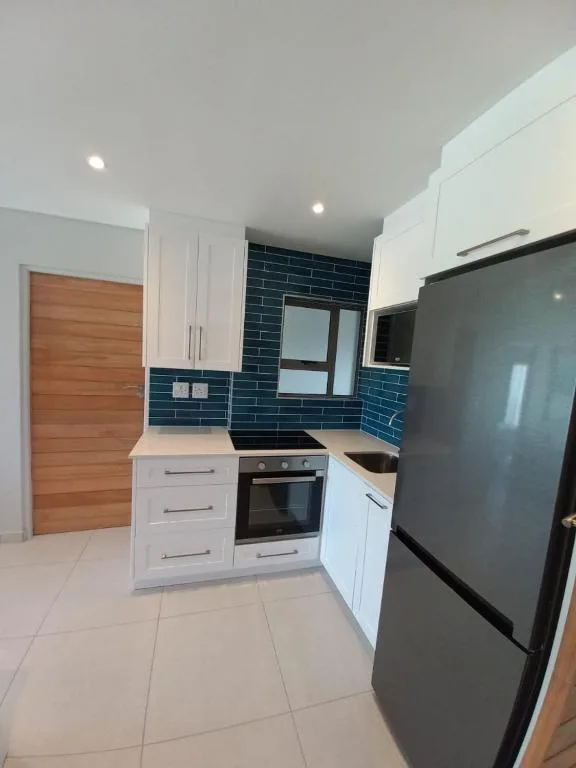Modern kitchen with white cabinetry, dark blue tile backsplash, and stainless steel appliances