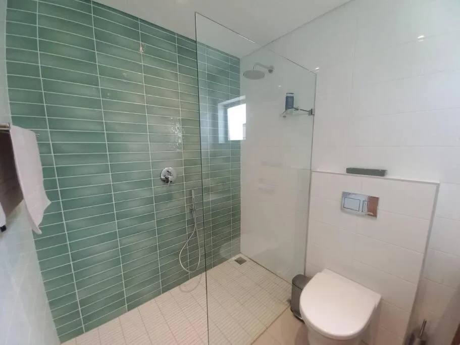 Modern bathroom with green tiled shower enclosure and white toilet