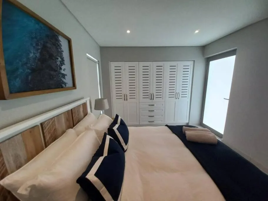 Modern bedroom with twin beds, built-in wardrobes, and coastal artwork