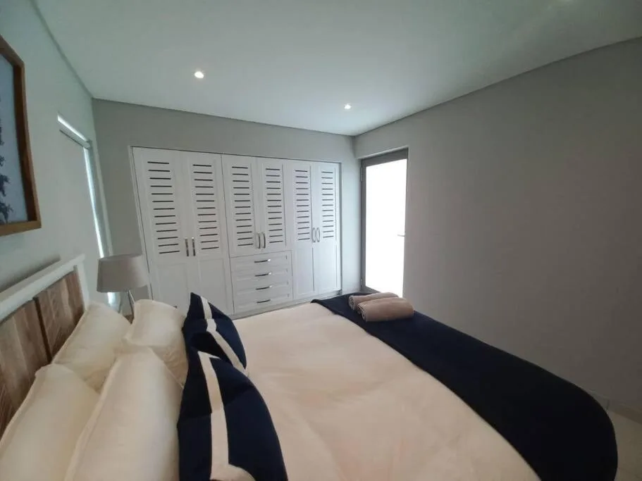 Modern bedroom with double bed, white built-in wardrobes, and bright natural light