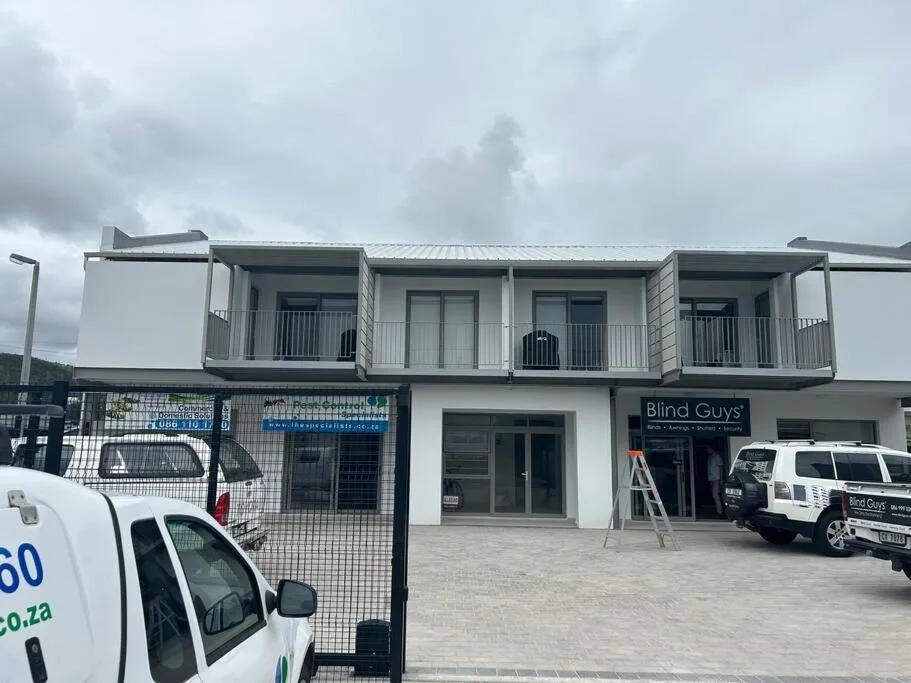 Modern white apartment building with balconies and commercial storefronts below