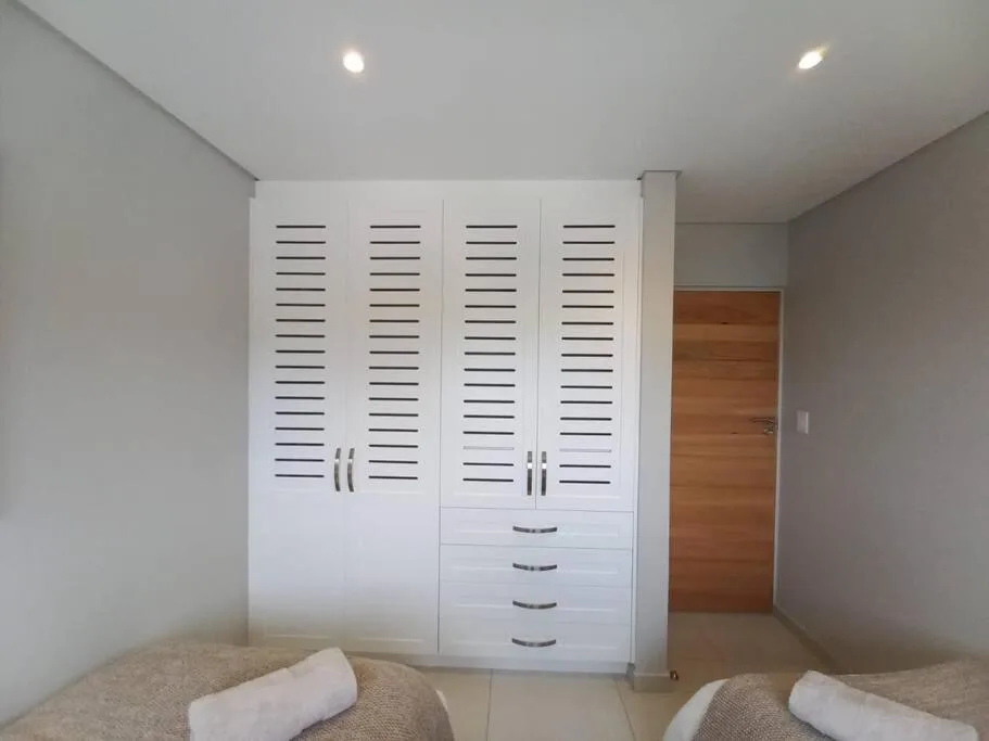Modern bedroom with twin beds and built-in white wardrobe storage