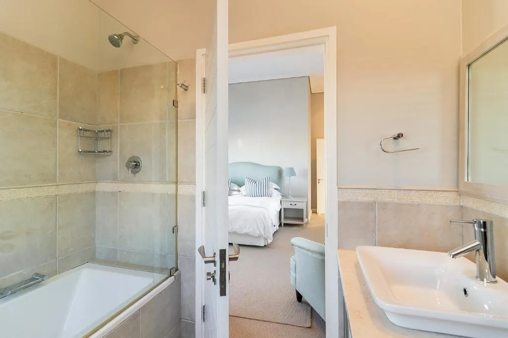 Modern bathroom with glass shower enclosure, white vanity sink, and bathtub