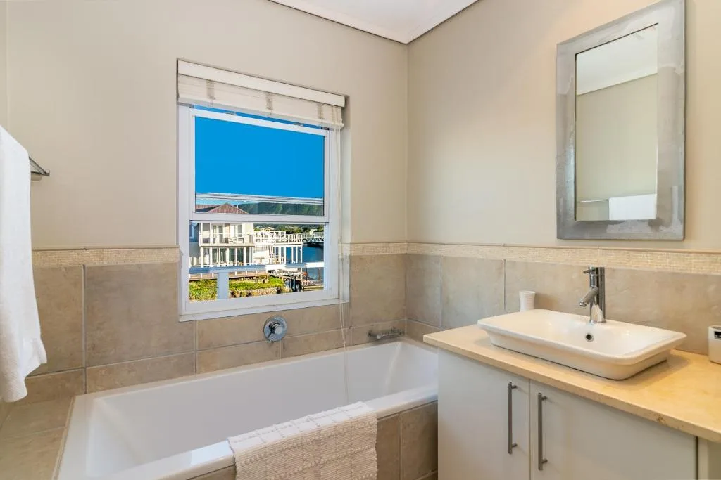 Modern bathroom with bathtub, vessel sink, and waterfront window view