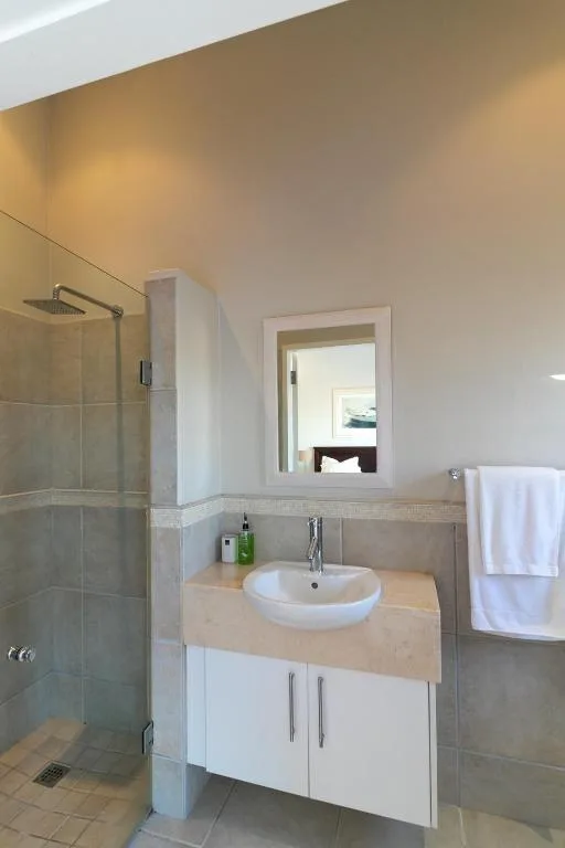 Modern bathroom with round sink vanity, glass shower enclosure, and mirror