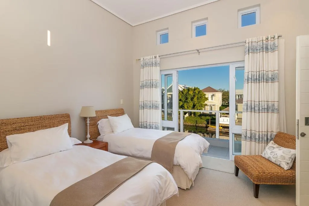 Bright twin bedroom with woven headboards overlooking garden and neighborhood