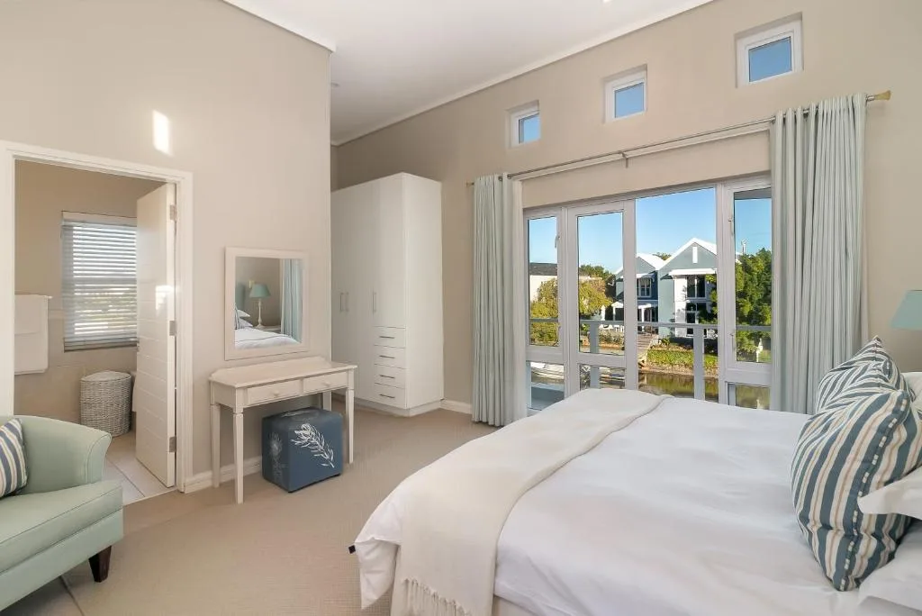 Bright bedroom with water views through large glass doors and windows