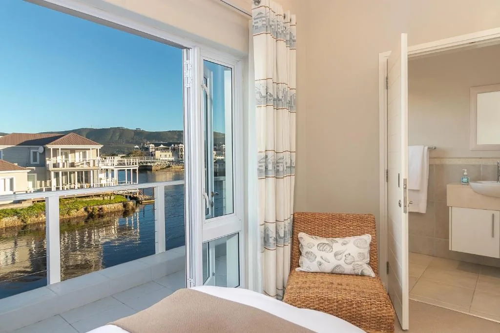 Bedroom with water view through glass doors opening to deck