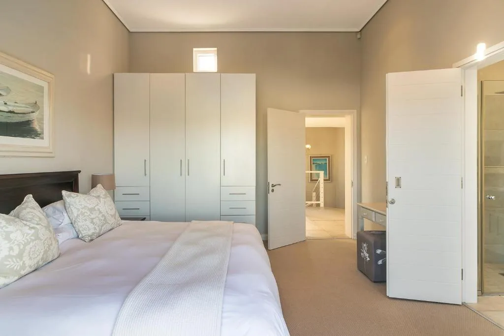 Spacious bedroom with queen bed, white wardrobe, and ensuite bathroom access