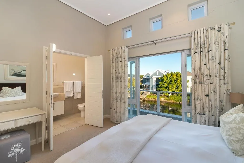 Bright bedroom with waterfront views through large glass doors and windows