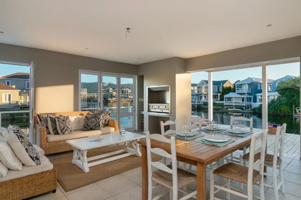 Waterfront deck with dining table, lounge seating, and lagoon views