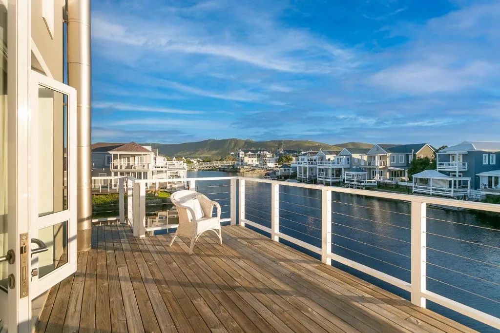 Waterfront deck with white railing overlooking lagoon and residential buildings