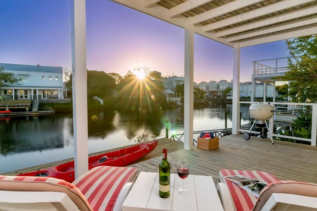 Waterfront deck with loungers, sunset view over lagoon and boats