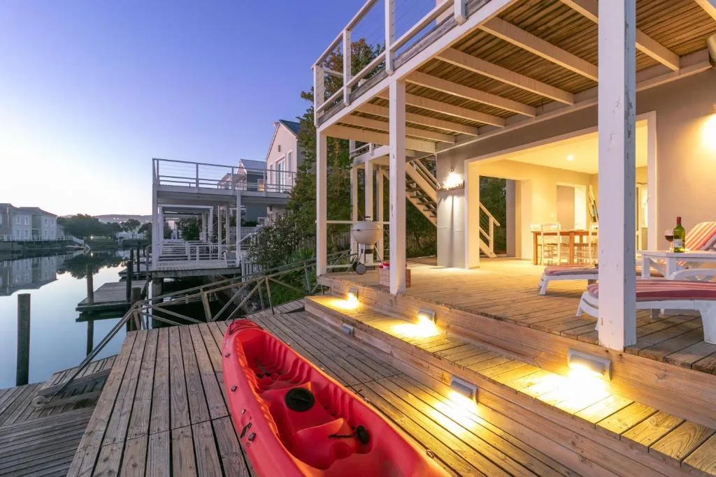 Waterfront deck with kayak, lighting, and evening lagoon view