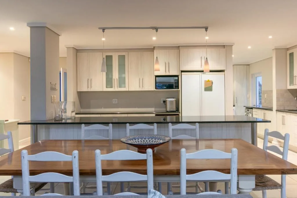 Spacious dining table with blue chairs overlooking modern kitchen