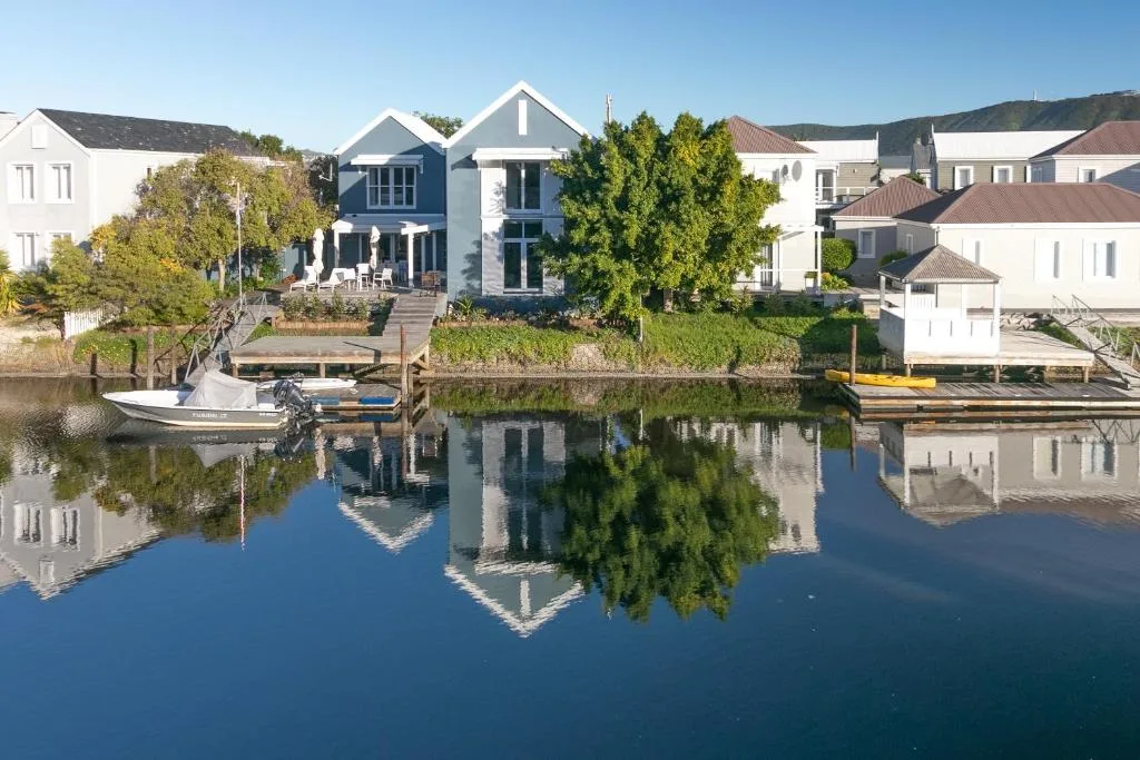 Modern waterfront villa with blue and white facade reflected in calm lagoon waters