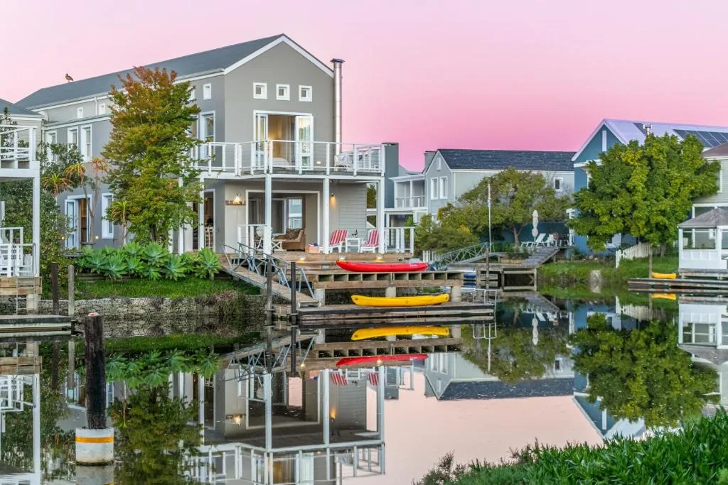 Waterfront villa with dock, kayaks, and pink sunset sky reflected in water