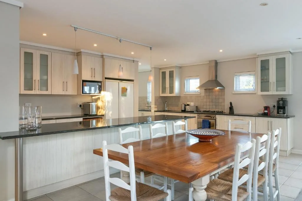 Modern kitchen with cream cabinetry, black countertops, and dining table