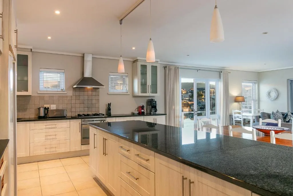 Modern kitchen with white cabinetry, dark countertops, and pendant lights