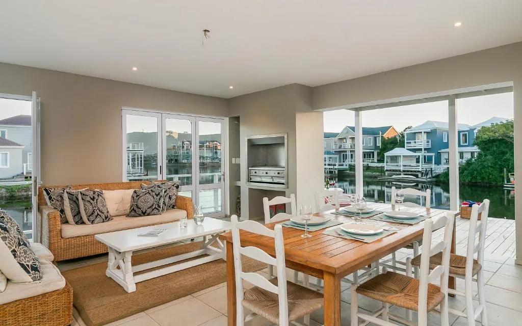 Open-plan living area with wicker sofa, dining table, and waterfront views