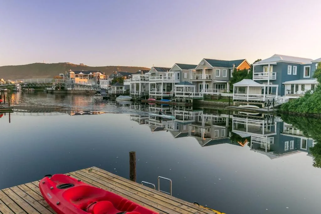 Waterfront homes reflected in calm lagoon water at sunset