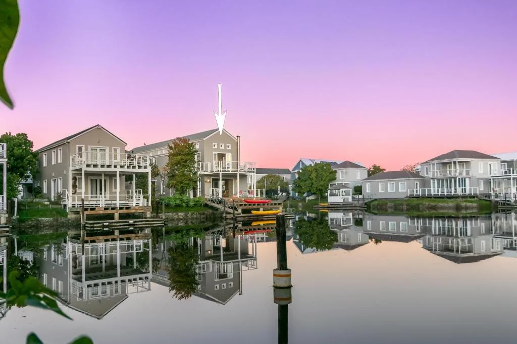 Waterfront village at sunrise with colonial-style houses reflected in still water