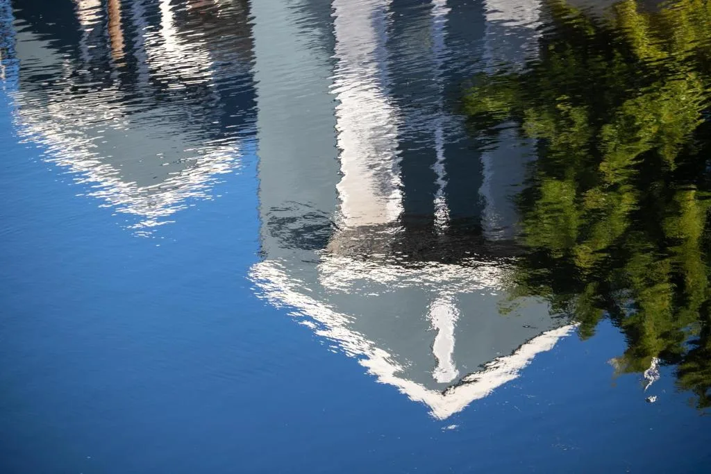 Waterfront property reflection with blue sky and lush green vegetation