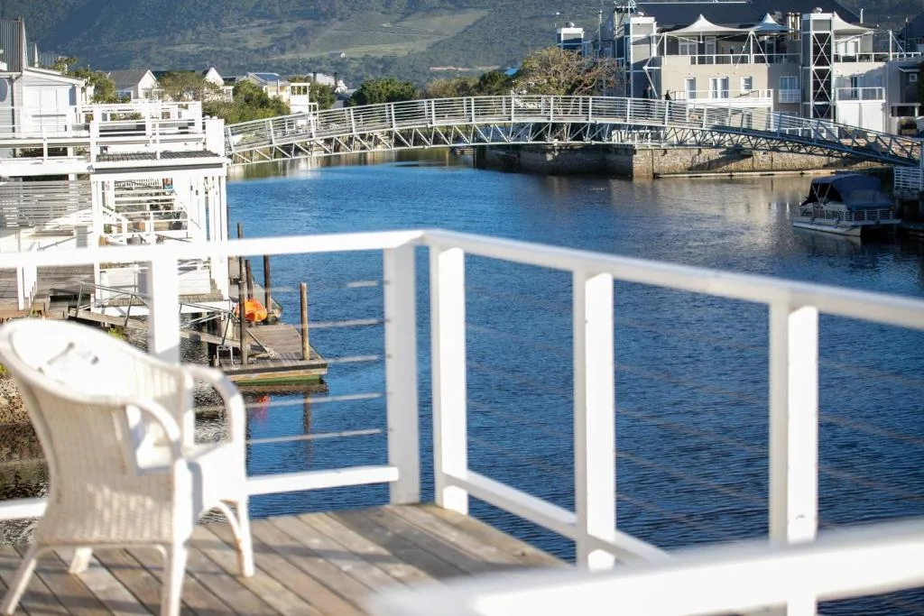 Scenic waterfront view from private deck overlooking blue lagoon and pedestrian bridge