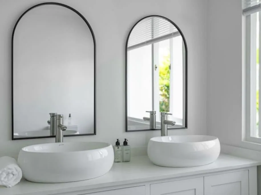 Modern double bathroom vanity with round white basin sinks and arched mirrors
