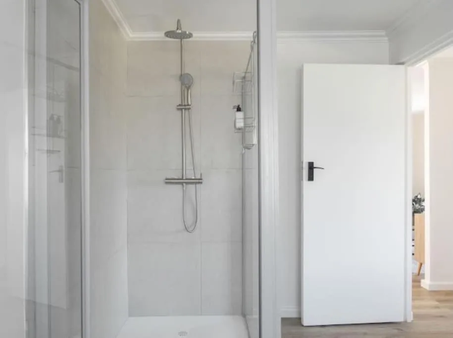 Modern glass-enclosed shower with rainfall showerhead and chrome fixtures