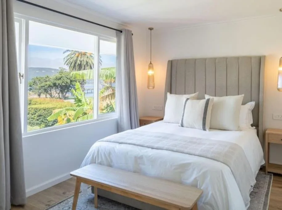 Bright bedroom with comfortable bed, coastal views through large windows