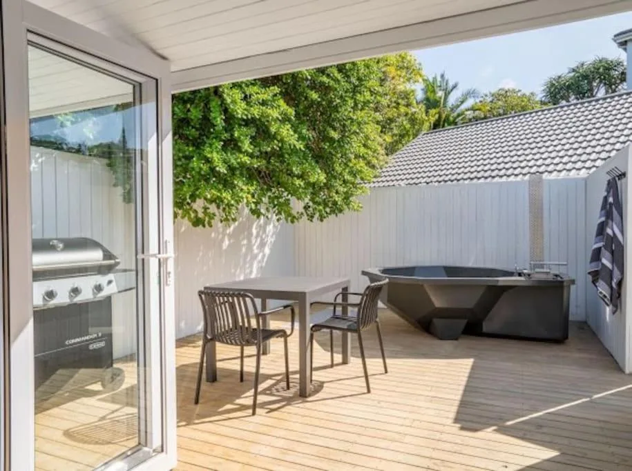 Wooden deck with dining table, chairs, and hot tub area overlooking garden