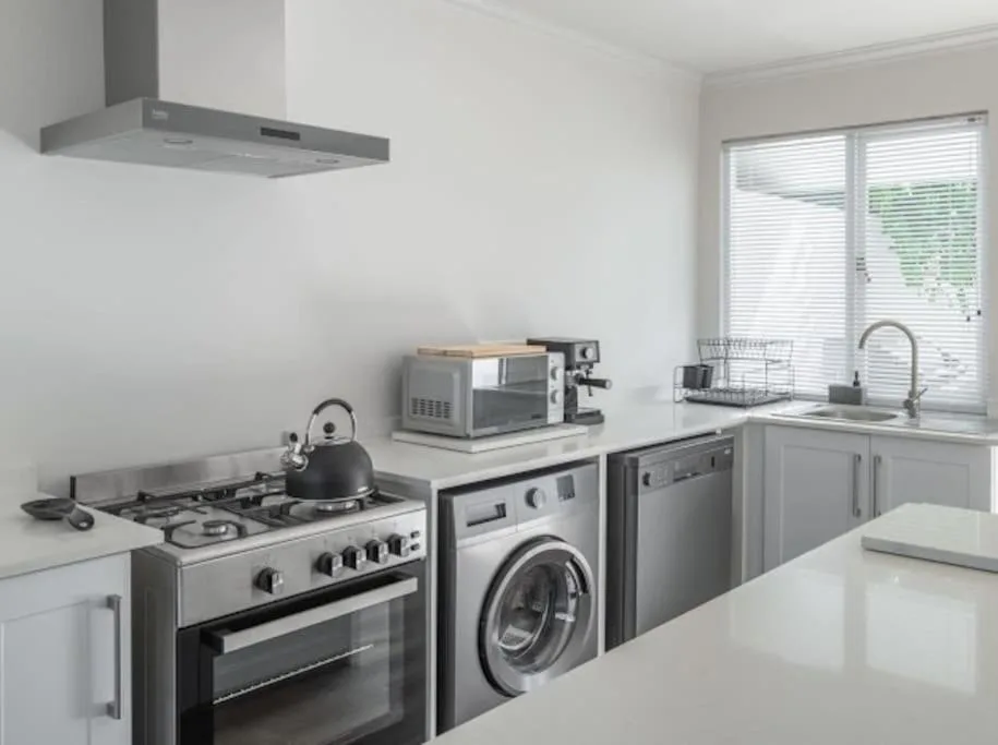Modern kitchen with gas cooktop, oven, washing machine, and microwave appliances