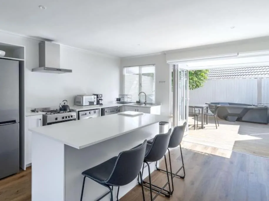 Modern open-plan kitchen with white cabinetry, stainless steel appliances, island seating