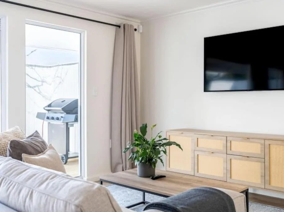 Modern bedroom with bed, TV, and lagoon view through glass doors