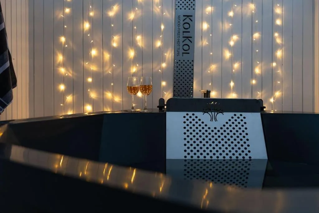 Elegant black bathtub with champagne glasses and warm string lights backdrop