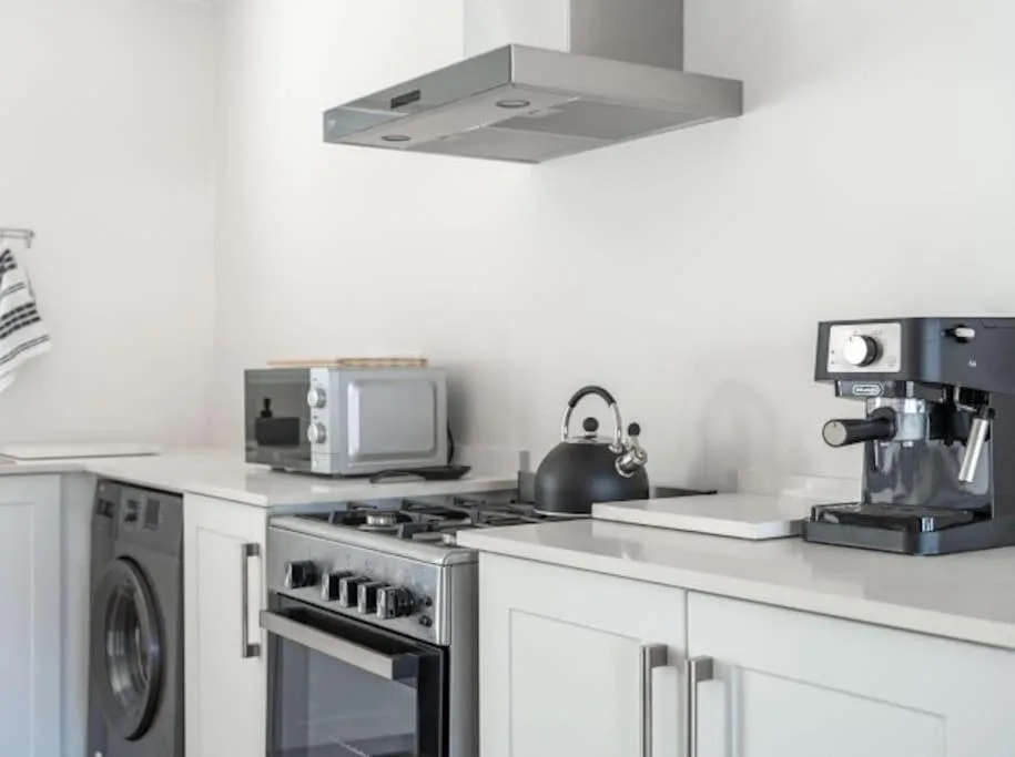 Modern kitchen with stove, microwave, kettle, and espresso machine