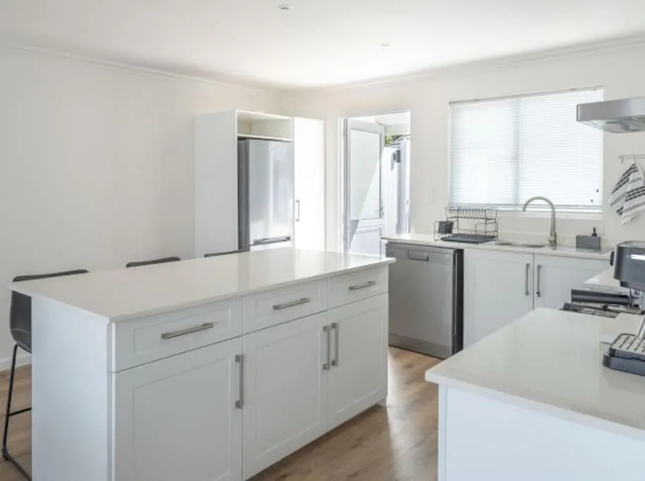 Modern white kitchen with island bench and stainless steel appliances