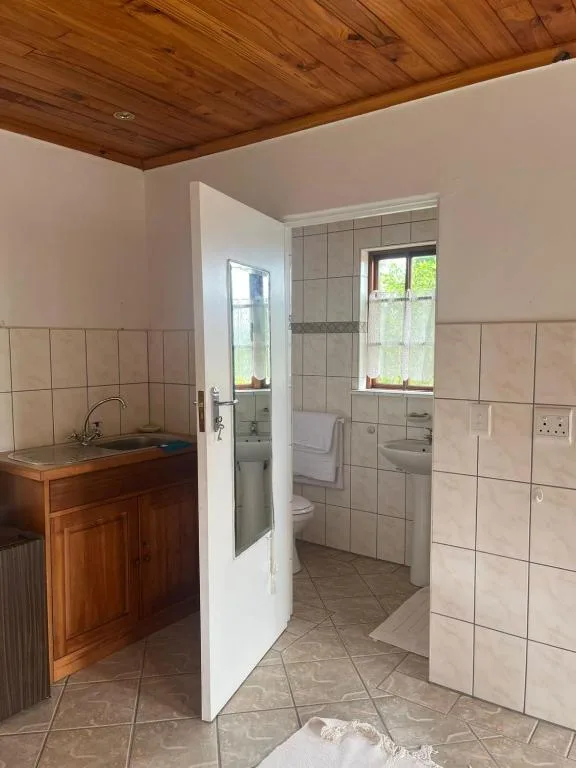 Spacious bathroom with tiled walls, wooden ceiling, and separate shower enclosure