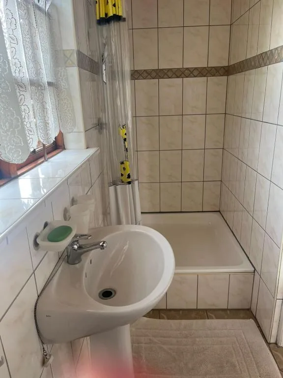 Compact bathroom with pedestal sink, shower cubicle and tiled walls