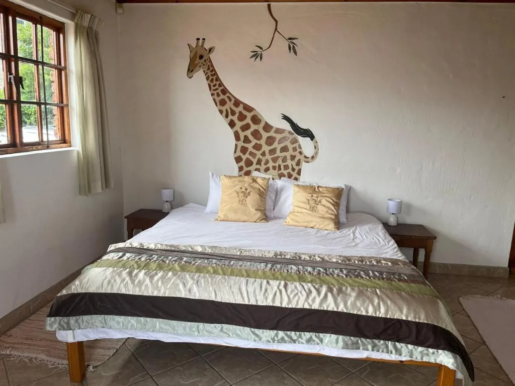 Bedroom with queen bed, giraffe wall mural, and natural light from window