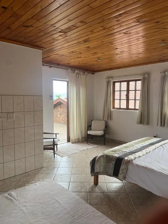Spacious bedroom with wooden ceiling and tiled floor areas