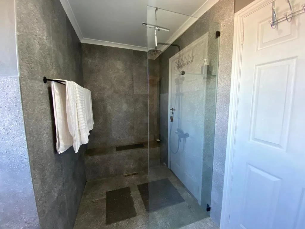 Modern walk-in shower with glass enclosure and rainfall showerhead in spacious bathroom