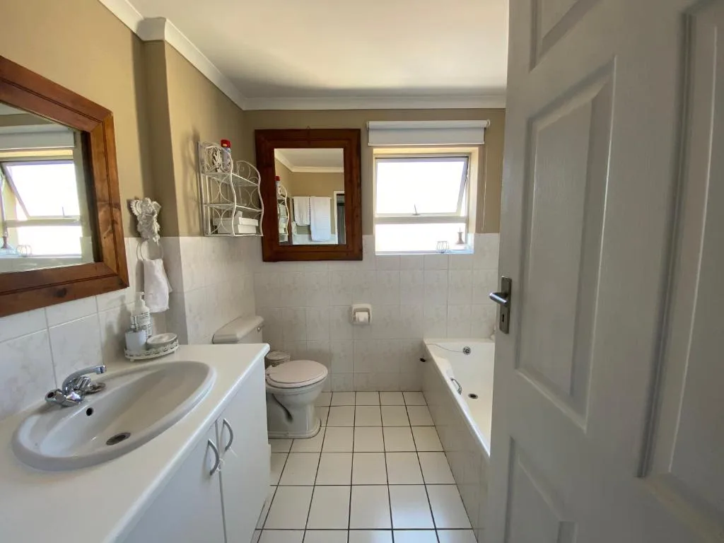 Bright bathroom with vanity, toilet, and bathtub along tiled floor