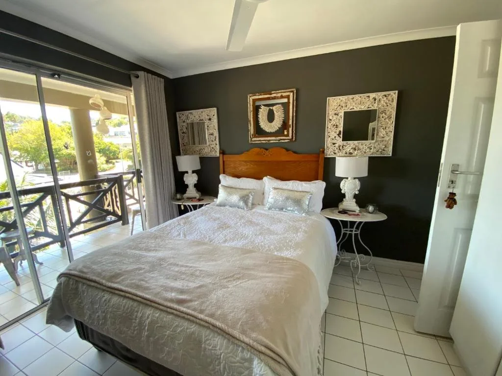 Elegantly appointed bedroom with wooden headboard and dark accent wall featuring deck access