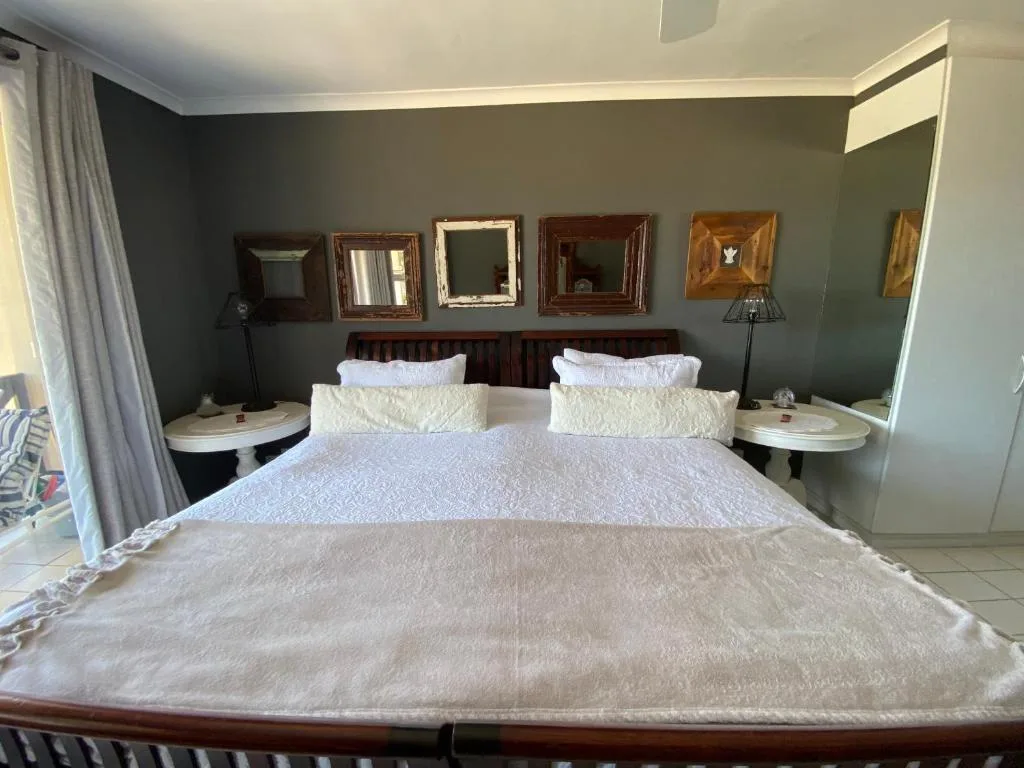 Spacious bedroom with queen bed, sage green walls, and decorative mirrors