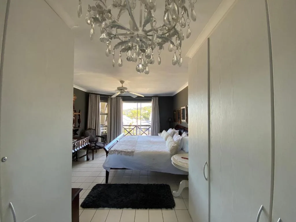 Spacious bedroom with elegant chandelier, king bed, and ocean view balcony doors
