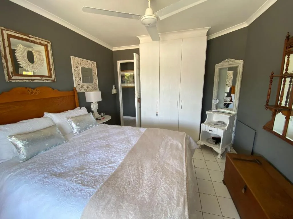 Spacious bedroom with queen bed, wooden headboard, and white built-in wardrobe