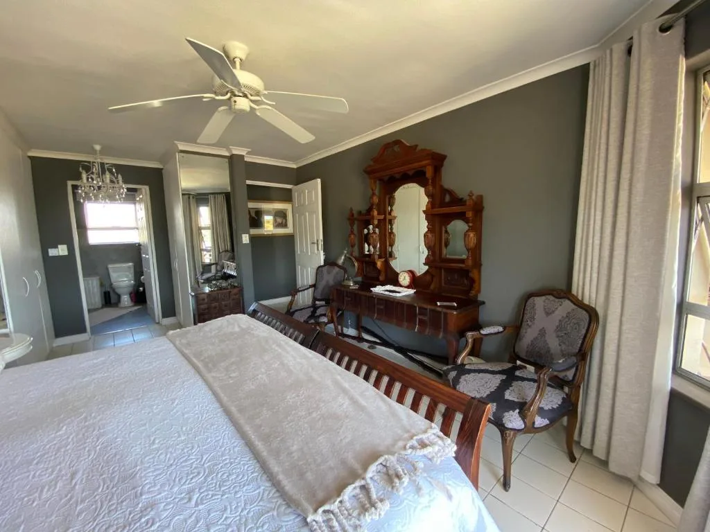 Spacious bedroom with wooden bed, antique dresser, and ceiling fan